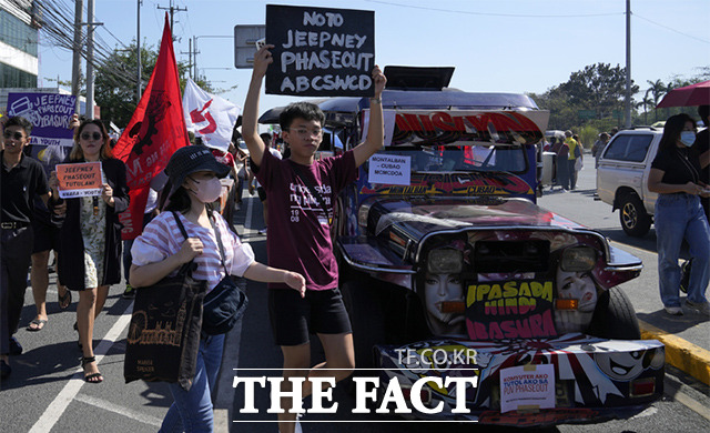 필리핀 대중교통 노조 등은 정부가 추진하고 있는 대중교통 현대화와 지프니의 단계적 폐지에 반대하며 일주일간 파업에 돌입했다. 한 운동가가 대중교통 파업 중인 지프니 옆에서 지프니 폐지 반대 피켓을 들고 있다. /케손시티=AP.뉴시스