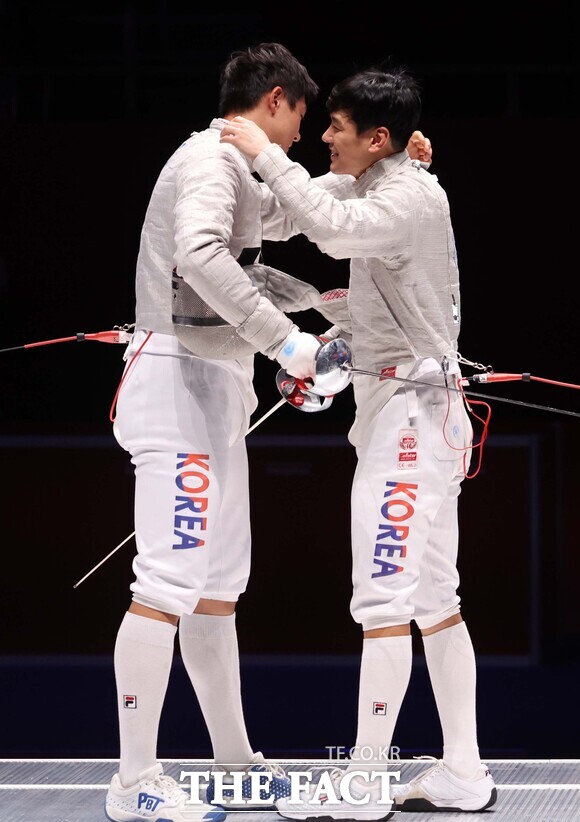 오상욱(왼쪽)이 25일 중국 항저우 디안즈대 체육관에서 열린 항저우 아시안게임 펜싱 남자 사브르 결승에서 구본길을 15-7로 꺾고 금메달을 확정지은 뒤 웃으면서 서로를 끌어안고 있다. /항저우=뉴시스