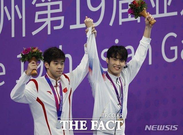 2022 항저우 아시안게임 남자 자유형 200m에서 금메달을 차지한 황선우(오른쪽), 은메달 중국 판잔러(왼쪽)가 27일 중국 항저우 올림픽 스포츠센터 수영장에서 열린 시상식에서 함께 손을 들고 있다. /항저우=뉴시스