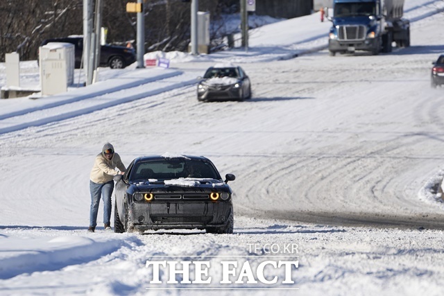 지난 16일(현지 시간) 미국 전역에 영향을 미치는 북극 한파와 겨울 폭풍으로 미 테네시주 내슈빌에서 20㎝의 눈이 내린 가운데 한 운전자가 눈길 위 자동차를 밀고 있는 모습. /AP. 뉴시스