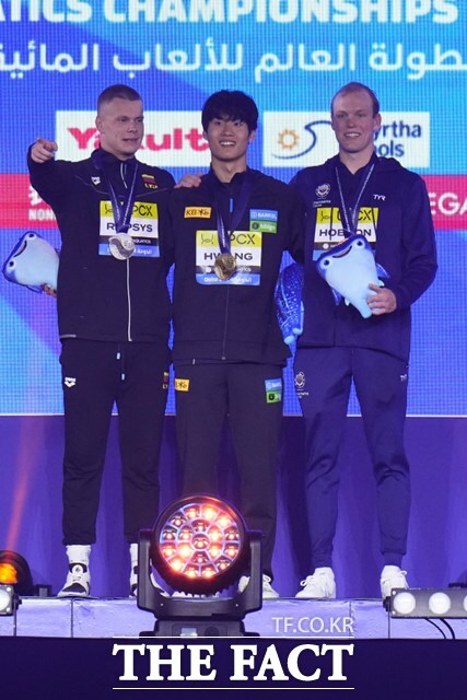 한국 수영 사상 최초로 세계선수권 자유형 200m에서 금메달을 목에 건 황선우(가운데)가 2위 랍시스(왼쪽), 3위 홉슨과 함께 시상대에서 포즈를 취하고 있다./도하=AP.뉴시스