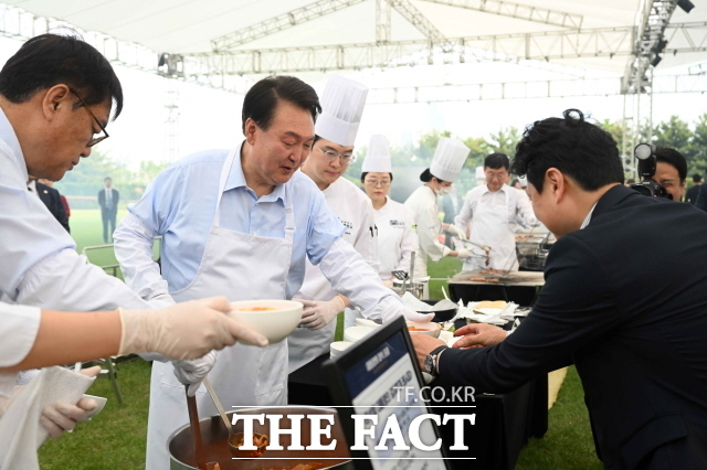 윤석열 대통령이 24일 서울 용산 대통령실 잔디마당에서 열린 출입기자단 초청 만찬 간담회에서 김치찌개를 출입기자들에게 배식하고 있다. 윤 대통령은 당선인 시절 김치찌개 간담회를 열자고 약속한 바 있다. /대통령실 제공