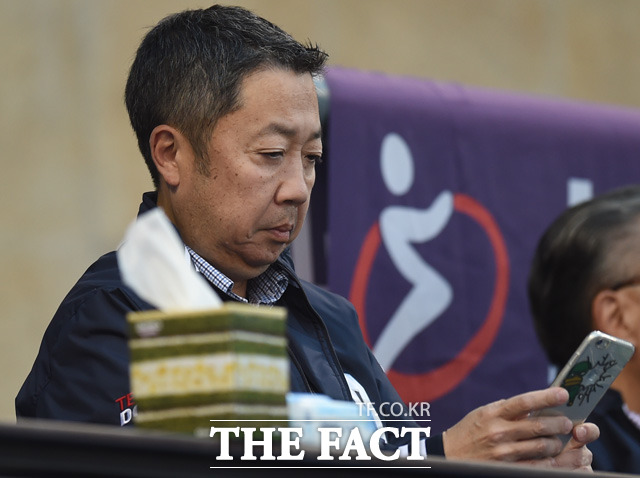 박정원 두산그룹 회장이 관중석에서 경기를 지켜보며 모바일 뉴스를 살펴보고 있다.