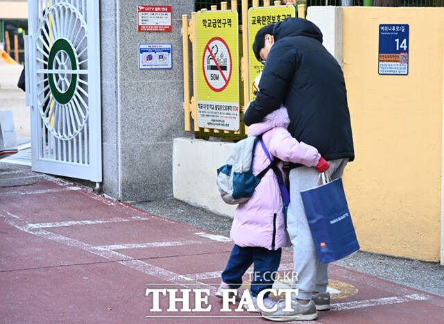 비상계엄령이 해제된 4일 오전 서울 영등포구의 한 초등학교 앞에서 한 아버지가 등교하는 자녀와 포옹하고 있다.