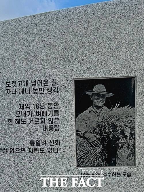 동대구역 광장에 세워진 박정희 전 대통령 동상 둘레석에 새겨진 사진과 글귀. 조각가 이상태 씨는 1965년 9월 30일 박 전 대통령이 추수하는 모습을 담은 이 사진을 참조해 동상을 제작했다고 밝혔다, / 박병선 기자