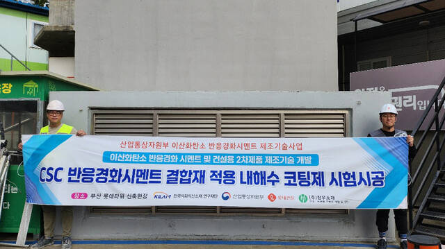 롯데건설은 국책연구과제인 산업통상자원부 한국산업기술평가관리원의 이산화탄소 반응 경화 시멘트 및 건설용 2차 제품 제조기술 개발에 공동연구사로 참여하고 있다고 7일 밝혔다. 사진은 롯데건설 직원들이 부산 롯데타워 현장에서 이산화탄소 반응경화 시멘트를 활용한 코팅제를 시공하고 기념촬영을 하고 있는 모습. /롯데건설