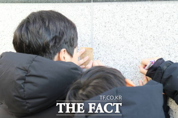 11일 대전 초등생 살해 사건이 발생한 대전 서구의 한 초등학교 앞에는 피해자인 고(故) 김하늘 양을 추모하기 위한 국화꽃과 각종 간식, 쪽찌들이 놓여 있는 가운데 같은 학교의 학생들이 김 양을 추모하기 위한 쪽찌를 적고 있는 모습./정예준 기자