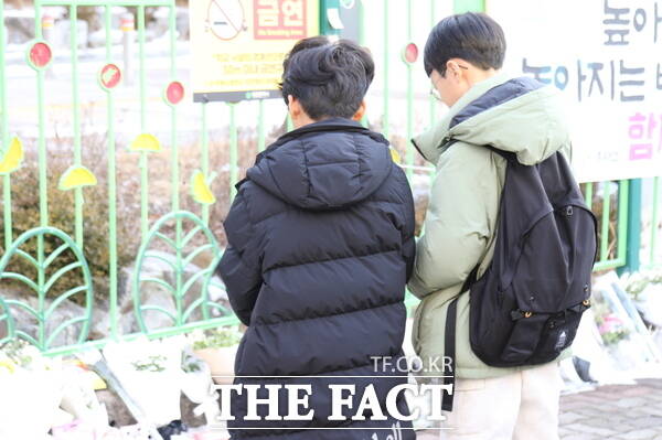 11일 대전 초등생 살해 사건이 발생한 대전 서구의 한 초등학교 앞에는 피해자인 고(故) 김하늘 양을 추모하기 위한 국화꽃과 각종 간식, 쪽지들이 놓여있는 가운데 같은 학교 학생들이 김 양을 위해 묵념을 하고 있는 모습./정예준 기자