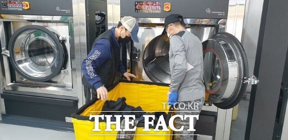 경기도 내 한 블루밍 세탁소를 찾은 노동자들이 작업복 세탁을 위해 세탁기에 넣고 있다. /경기도