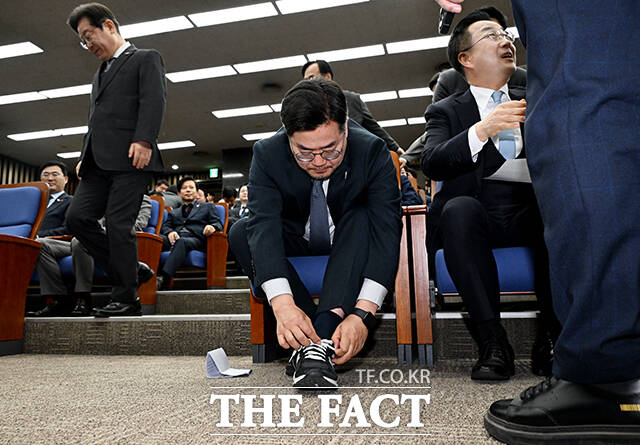 박찬대 더불어민주당 원내대표(가운데)가 4일 오후 서울 여의도 국회에서 열린 비상의원총회에 참석해 신발끈을 고쳐 매고 있다. /국회=배정한 기자