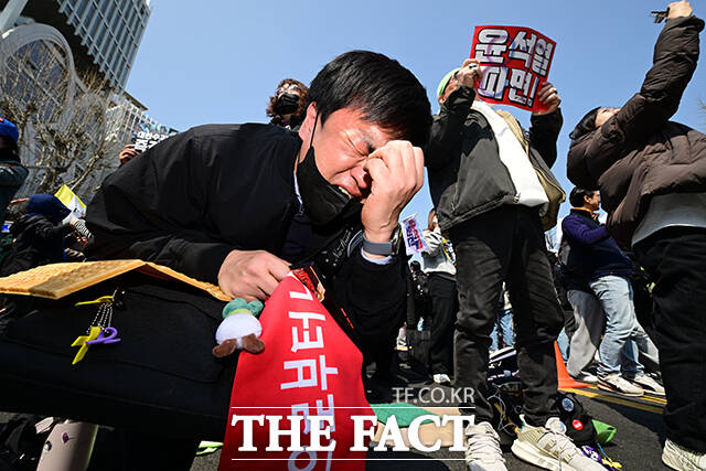 윤석열 전 대통령의 파면 결정이 이뤄지자 한 시민이 주저앉아 포효하고 있다.