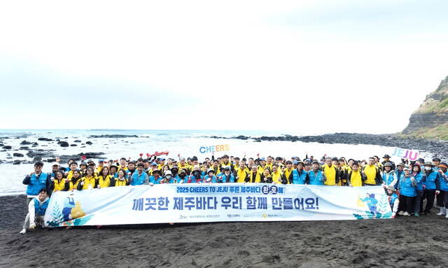 지난 17일 제주시 한경면 고산리 수월봉 인근 해안변에서 정화활동을 마친 오비맥주 임직원, 제주특별자치도 세계유산본부, 제주폐가살리기사회적협동조합, 한경면 주민 등 200여 명이 기념 촬영하고 있다. /오비맥주