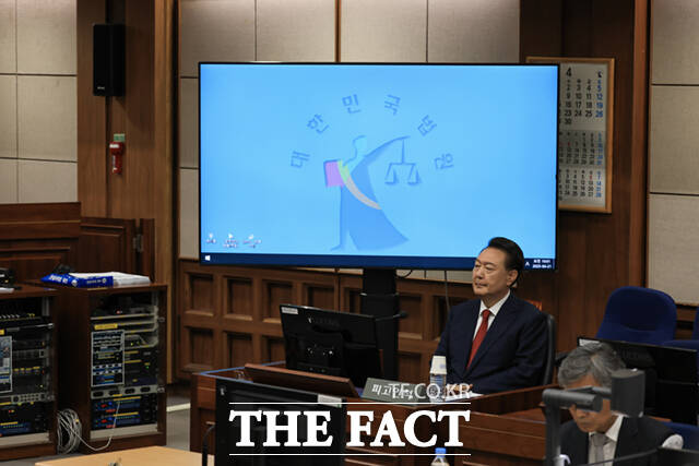윤석열 전 대통령이 21일 서초동 서울중앙지법에서 열린 내란 우두머리 혐의에 대한 두 번째 정식 재판에 출석해 피고인석에 착석해 있다. 피고인 석 뒤의 모니터에는 정의의 여신 상징물이 보이고 있다./사진공동취재단