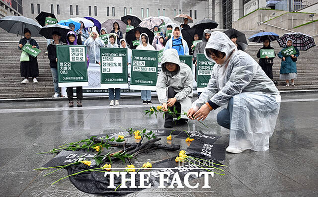 기후위기비상행동이 55주년 지구의 날을 맞은 22일 오전 서울 광화문 세종문화회관 앞에서 경북 산불로 탄 나뭇가지 주변에 꽃을 놓는 퍼포먼스를 하고 있다. /임영무 기자