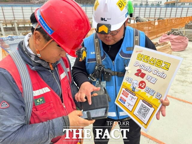 DL이앤씨 현장 안전관리자가 근로자에게 안전신문고 활성화 캠페인에 대해 설명하고 있다. /DL이앤씨