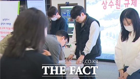 남양주시 공직자들이 상수원 규제 개선을 위한 헌법소원의 심리가 조속히 이뤄지기를 촉구하는 서명부에 서명을 하고 있다. /남양주시