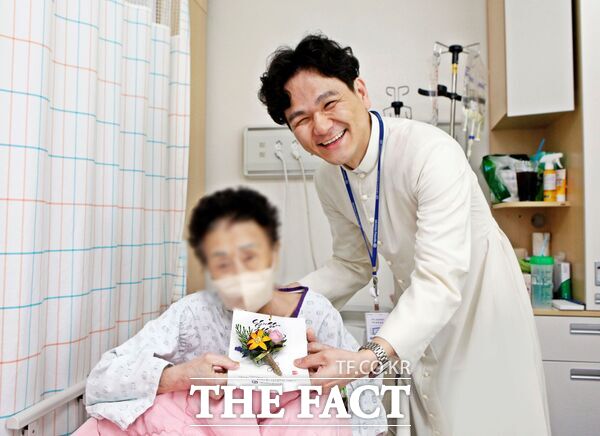 가톨릭대 대전성모병원 원목실 김제동 실장신부가 8일 입원환자에게 카네이션을 전달하고 기념촬영을 하고 있다./대전성모병원