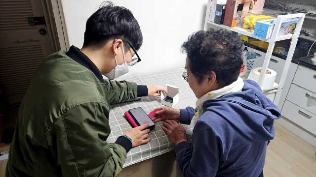 사회적 고립 가구를 방문해 모바일 앱 설치를 도와주는 모습. /마포구