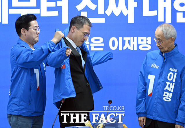 국민의힘 탈당 후 이재명 더불어민주당 대선 후보 지지에 이어 민주당에 입당한 김상욱 의원(가운데)이 19일 서울 여의도 더불어민주당 중앙당사에서 열린 중앙선거대책위원회의에 참석해 박찬대 원내대표의 도움으로 당 점퍼를 착용하고 있다. 오른쪽은 윤여준 총괄상임선거대책위원장. /박헌우 기자