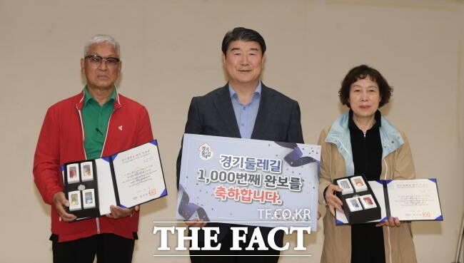 조원용(가운데) 경기관광공사 사장이 20일 경기둘레길 전 구간 완보자 성판득 씨(999번째 완보자)와 이은영 씨(1000번째 완보자)에게 기념품 등을 전달하고 있다. /경기관광공사