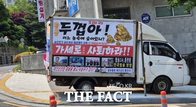 금두꺼비 매관매직을 연상시키는 현수막으로 뒤덮은 차량이 태안군청 정문 맞은편에 정차해 있는 모습./ 이수홍 기자