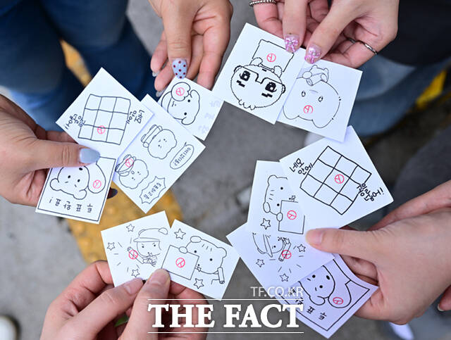 사전투표를 마친 시민들이 도장을 찍은 캐릭터 그림을 들고 기념촬영하고 있다. MZ세대(밀레니얼+Z세대)를 중심으로 연예인·캐릭터 등을 활용한 맞춤형 투표 인증 용지가 유행이다.