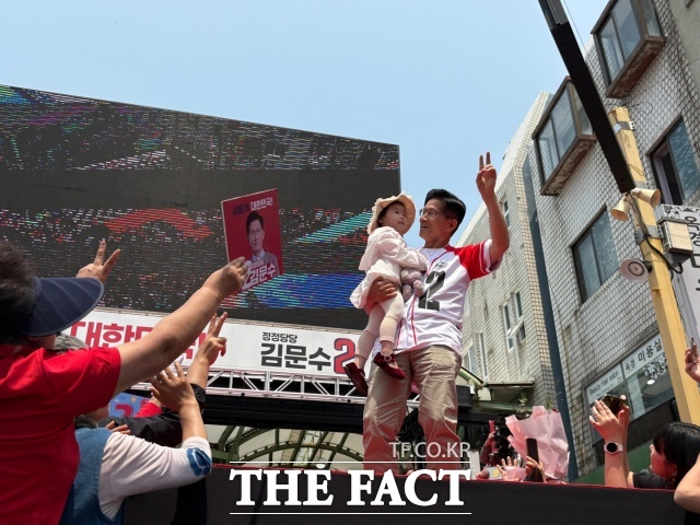 김문수 국민의힘 대선 후보가 31일 속초 관광수산시장 유세 현장에서 아이를 안고 지지자들을 향해 인사하고 있다. /속초=김수민 기자