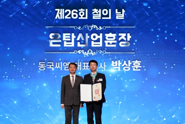 제26회 철의 날 행사에서 박상훈 동국씨엠 대표(오른쪽)가 은탑산업훈장을 받은 뒤 안덕근 산업통상자원부 장관과 기념사진을 촬영하고 있다. /동국씨엠