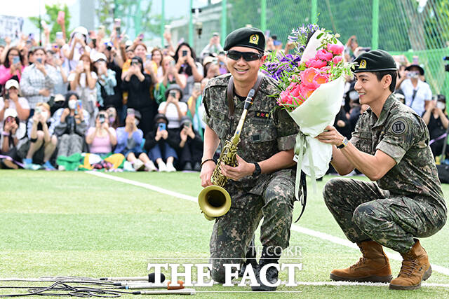 색소폰으로 전역을 자축한 RM과 뷔가 팬들 앞에서 미소짓고 있다.