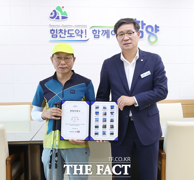 진병영 함양군수 오르GO 함양 1000번째 15좌 완등자 정진택 씨에게 기념품을 전달하고 있다./함양군