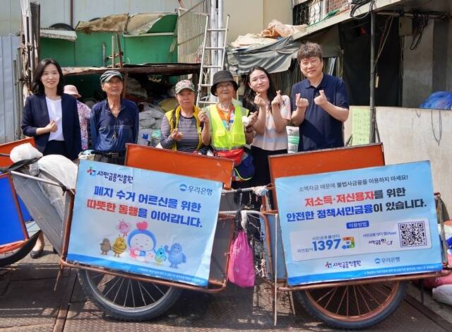 지난 19일 우리은행, 서민금융진흥원, 협동조합 끌림이 함께 폐지수거 어르신들에게 경량 리어카와 안전용품을 제공했다. 하현신 우리은행 상생금융부장(왼쪽)과 신승주 서민금융진흥원 홍보협력실장(오른쪽)이 전달식 이후 어르신들과 함께 기념사진을 촬영하고 있다. /우리은행