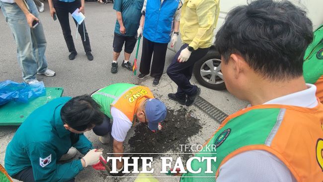 부천시 직원들과 자율방재단원들이 빗물받이 내 퇴적물을 제거하고 있다./부천시