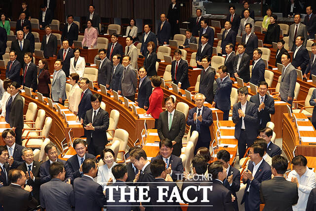 본회의장 입장하는 이재명 대통령과 인사하는 더불어민주당 의원들과 그 모습을 바라보는 국민의힘 의원들.