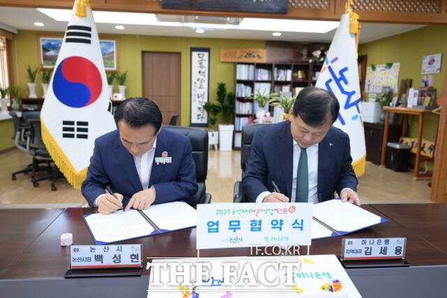 백성현 논산시장(왼쪽)과 김세용 하나은행 대전영업본부 지역대표가 26일 논산시청 시장실에서 업무협약을 맺고 협약서에 사인을 하고 있다. /논산시