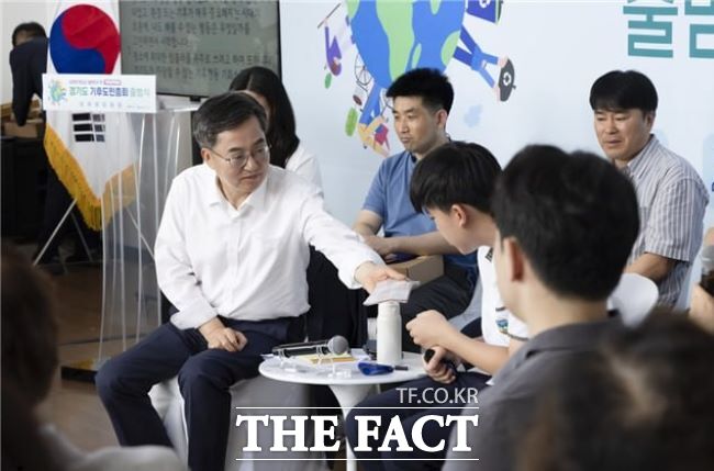 김동연 경기도지사가 지난달 30일 시흥에코센터에서 진행된 경기도 기후도민총회 출범식에서 땀 흘리는 학생 참가자에게 손수건을 건네고 있다. /경기도