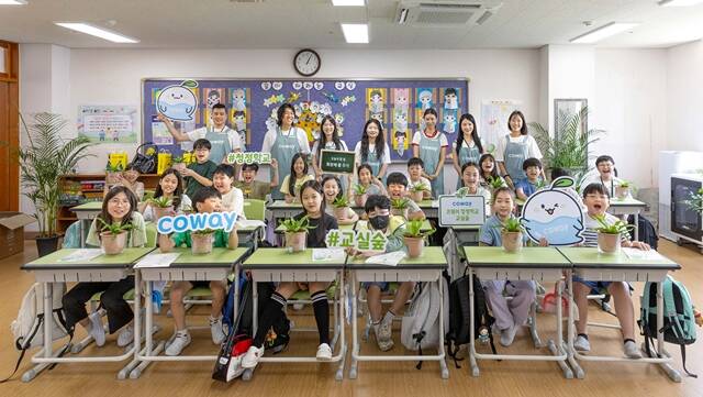 코웨이 임직원 봉사자들과 삼일초 학생들이 청정학교 교실숲 제7호 조성 기념 단체 사진을 촬영하고 있다. /코웨이