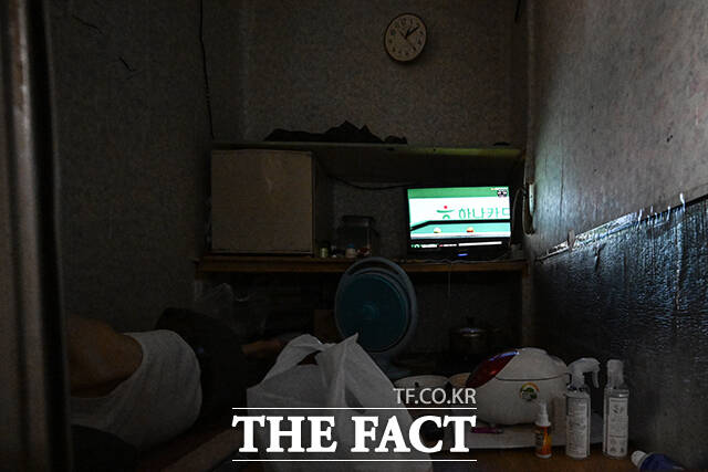 쪽방촌 주민이 선풍기 바람을 쐬고 있다.