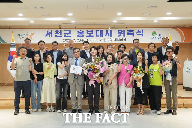 서천군이 트로트 가수 박민수를 지역 1호 홍보대사로 위촉한 가운데 2일 열린 위촉식에서 김기웅 서천군수, 팬클럽 비타민수 회원 등이 기념 촬영을 하고 있다. /서천군