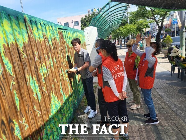 대전 대덕구 신탄진동 새마을협의회와 주민자치회원들이 신탄진역에서부터 석봉 과선교까지 200여m 구간을 수세미 터널과 벽화로 꾸민 힐링을 위한 명품 거리를 조성했다. 주민자치회원들이 벽화 그리기에 함께하고 있다. /한동권 독자
