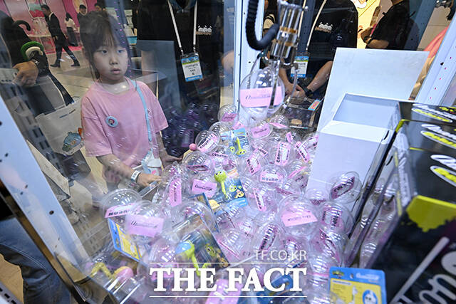어린이가 인형 뽑기 기계로 상품을 뽑고 있다.