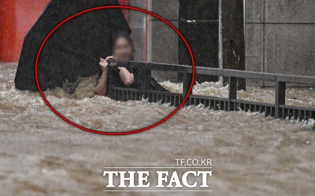 토요일인 19일은 전국이 대체로 흐리고 대부분 지역에서 비가 내리겠다. 경남과 광주를 중심으로 강하고 많은 비가 내릴 것으로 예보됐다. 사진은 지난 17일 하루동안 400mm가 넘는 폭우가 내린 광주에서 한 시민이 북구청 앞 도로에서 물살에 휩쓸려 난간을 붙잡아 버티고 있는 모습. /뉴시스