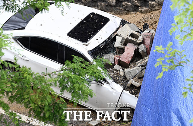 16일 저녁 시간당 41mm의 강한 비로 옹벽을 지지하던 토사가 침하돼 차량을 덮치는 사고가 발생한 가운데 18일 오전 경기 오산시 가장동 가장교차로 인근 사고 현장에는 흘러내린 벽돌과 토사가 차량 앞부분을 뒤덮고 있다. /오산=임영무 기자