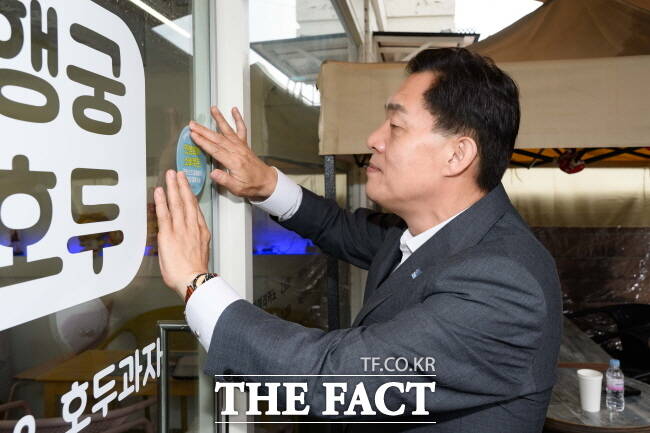 이재준 수원시장이 18일 행궁동의 한 민생회복소비쿠폰 사용처에 스티커를 부착하고 있다./수원시