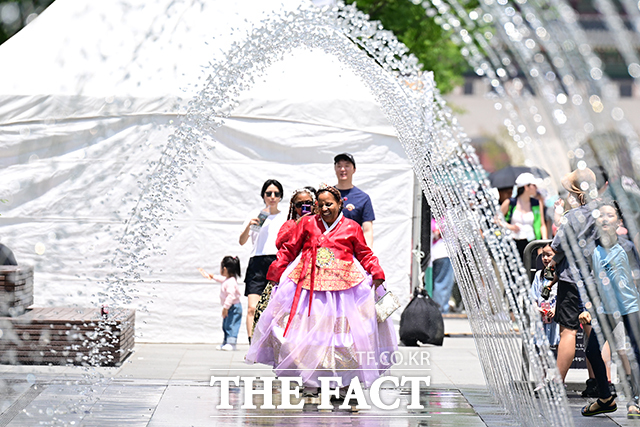 21일부터 민생회복 소비쿠폰 신청을 시작하는 가운데 외국인도 대상이라는 소식이 알려지면서 범위를 과도하게 넓혔다는 오해를 낳고 있다. 사진은 지난달 8일 오후 서울 종로구 광화문 광장 분수 터널을 찾은 외국인이 한복을 입고 기념촬영을 하는 모습. /남윤호 기자