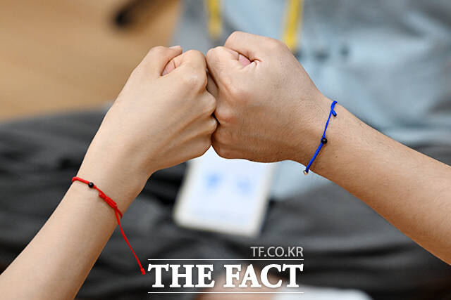 청실 홍실을 손목에 낀 참가자들이 게임 도중 주먹을 맞대고 있다.