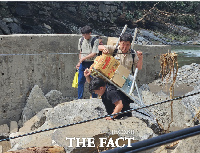 경기도 연인산도립공원 소속 공무원들이 폭우로 고립된 가평군의 중산리마을 어르신들을 위해 구호물품을 지게에 지고 운반하고 있다./경기도