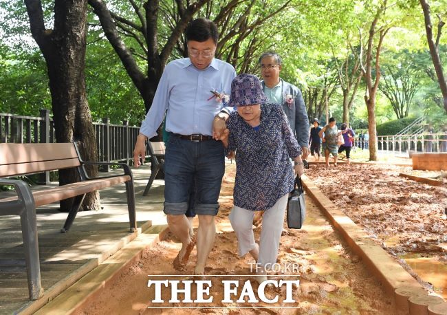 신상진(왼쪽) 성남시장이 한 맨발 황톳길 개장식에서 어르신과 황톳길을 걷고 있는 모습. /성남시