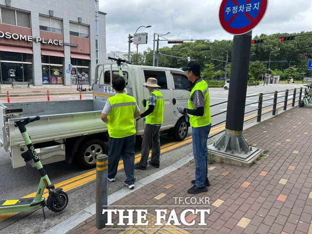 천안시 공무원들이 개인형 이동장치(PM) 지정주차제 시행 이후 무단 방치된 PM을 견인하고 있다./천안시