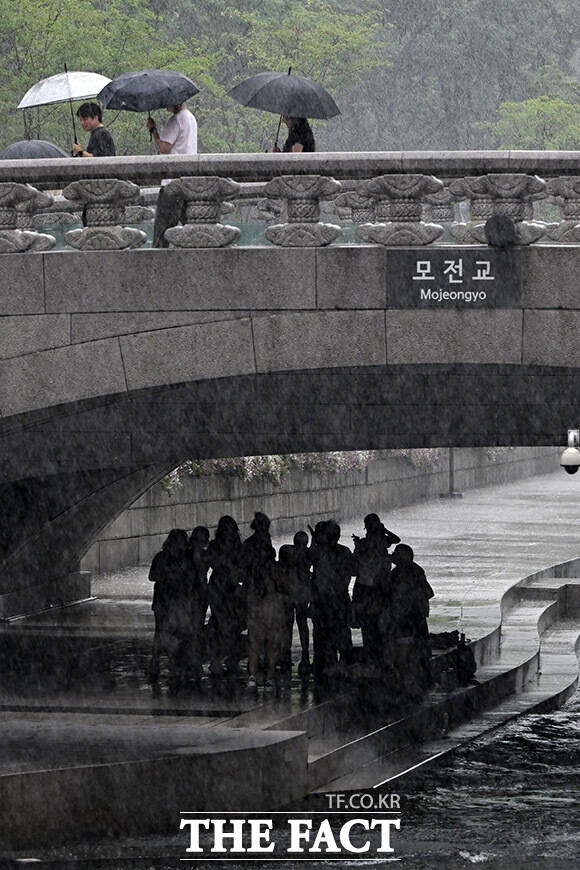 모전교를 사이에 두고 우산쓰고 이동하는 시민들(위)과 비를 피하는 시민들.