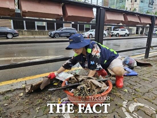 지난 13일 경기 고양시 안전보안관이 빗물받이에 쌓여 있는 낙엽과 쓰레기를 걷어내고 있다. /고양시